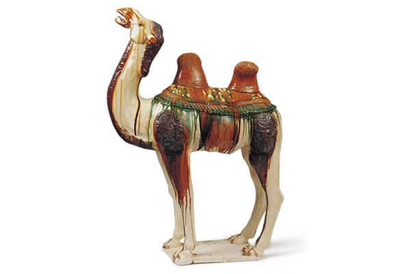 唐代．三彩骆驼+骆驼施以褐、绿、白等釉料，突显五官和肢体之特徵，局部可见釉料垂流的现象。（图四）